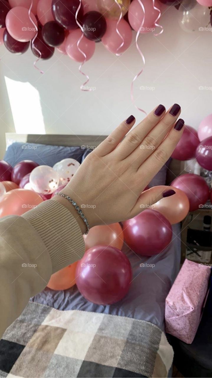 Hand with a bracelet on the background of a room full of balloons