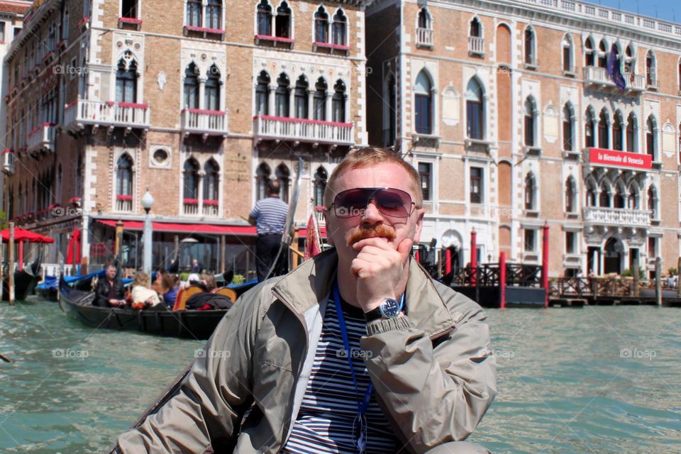 portrait of a man in sunglasses - my dad, on a gondola along the canals of Venice, old houses, architecture and history of Italy