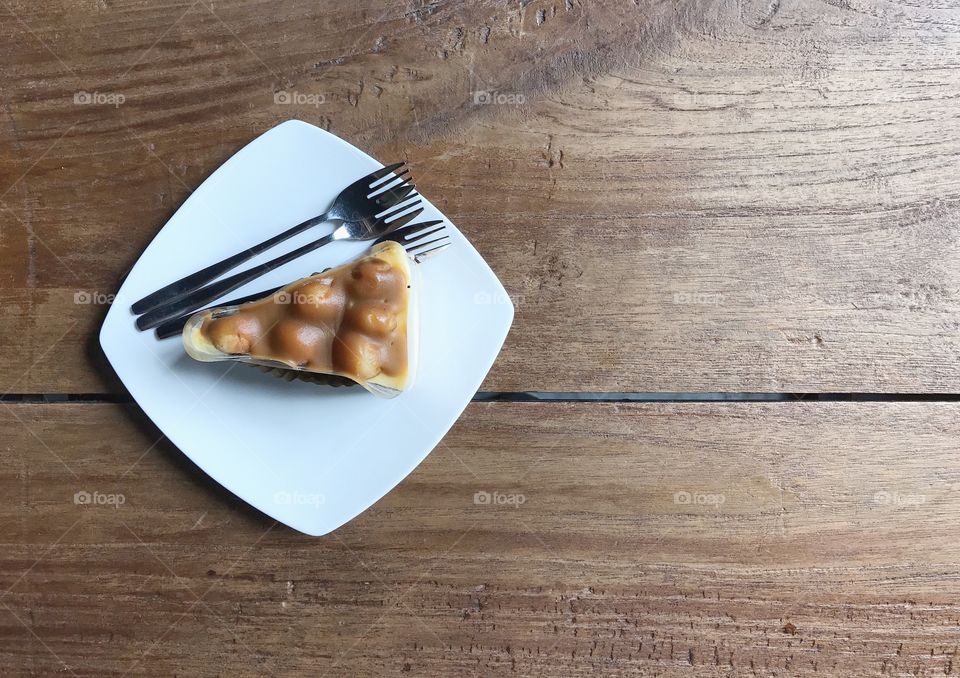 macadamia cake in white plate with forks on wood table 