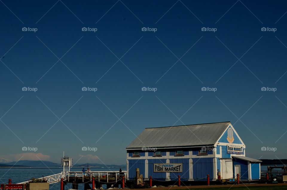 A very calm and clear blue sky features a fish market.