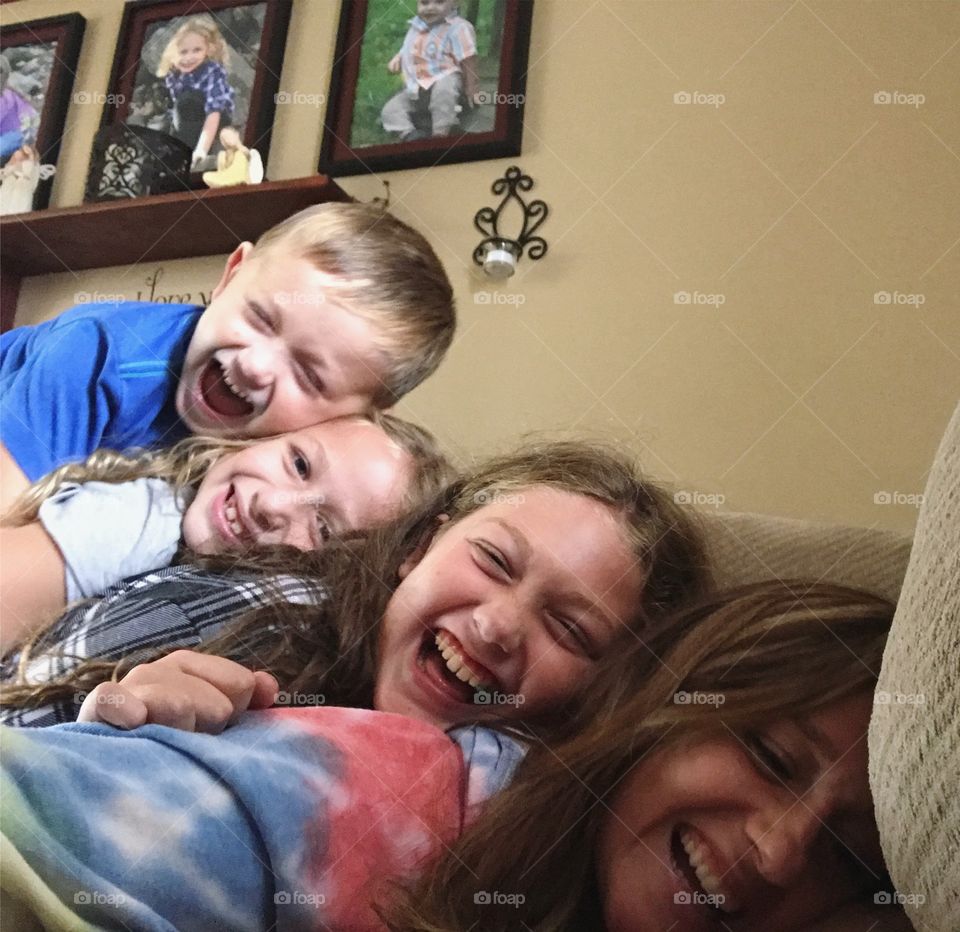 Brother and sisters laughing and playing at home in heap