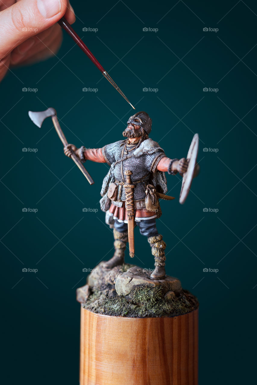Man painting a tiny figure of Viking