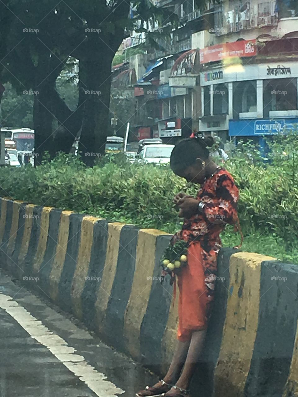 A girl selling flowers on the roads of India and being given an orange to eat 