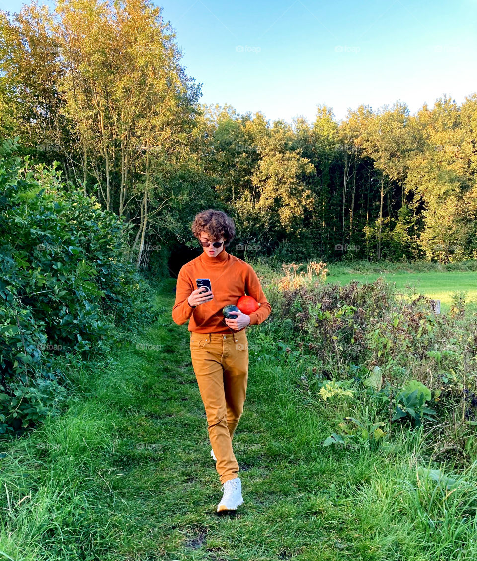 Boy walking in the forest with pumpkins
