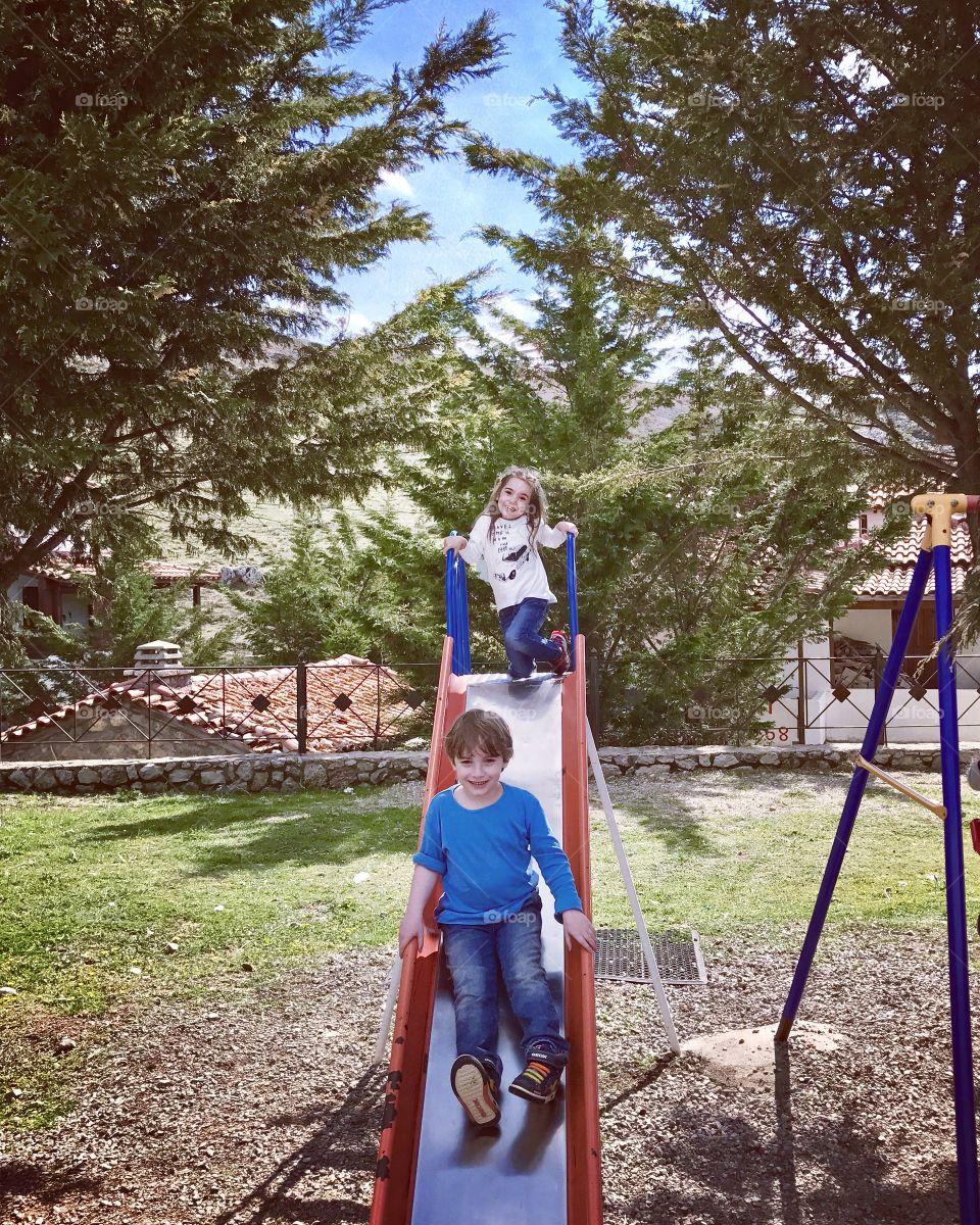 Boy and girl playing on slide in garden