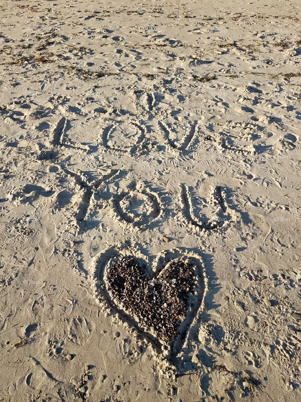 On one of my daily walks along the lake shore, I came across this familiar semtiment, creatively drawn in the sand. I love you was drawn in the sand, encircled by a large heart and a smaller heart, made with shells below it.