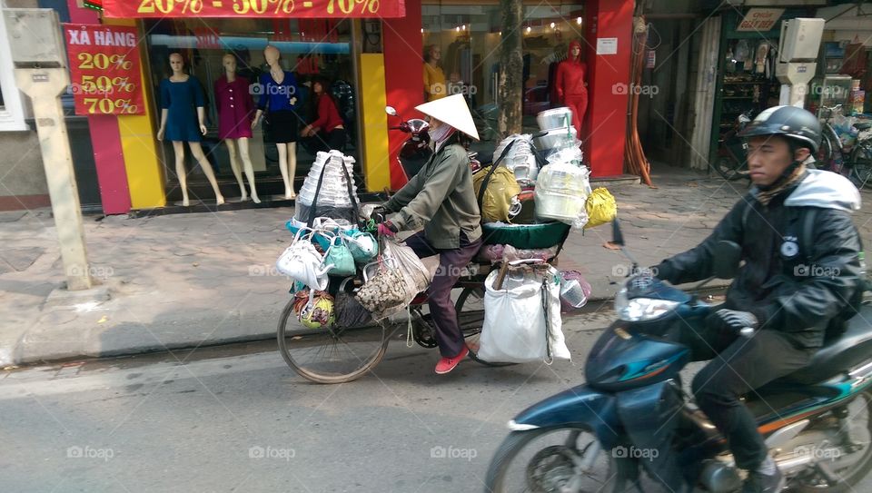 vietnam woman. a woman carry a lot ot if stuff on her bycycle