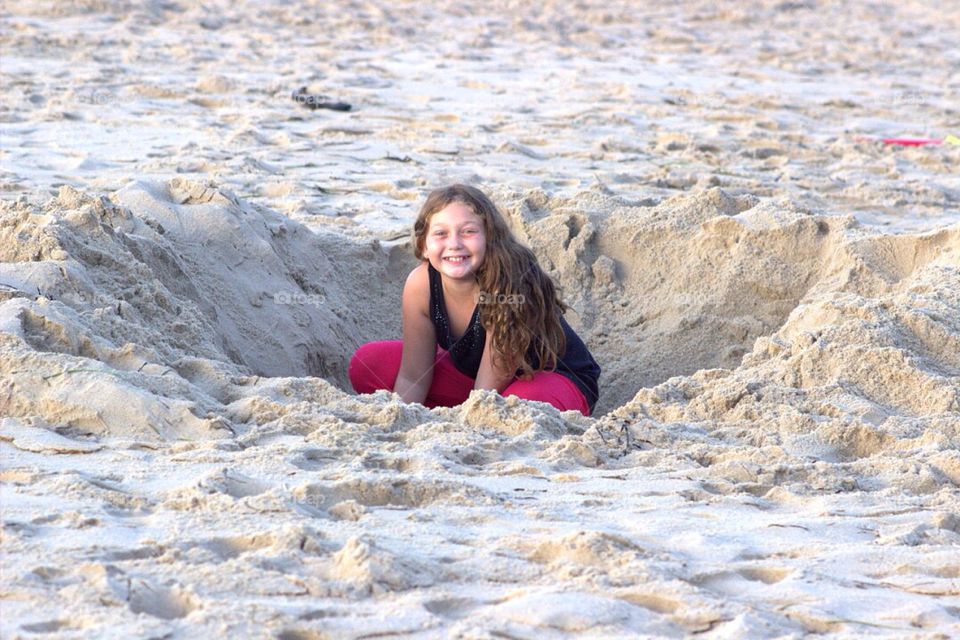 Girl digging in the sand on the beach