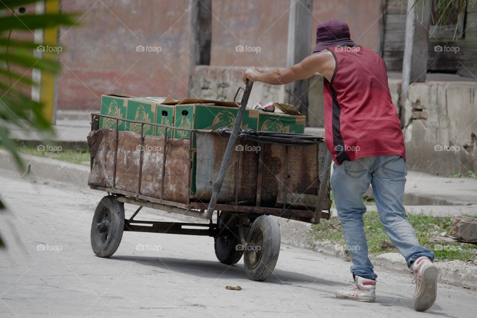 People In Cuba.Man pushing cart up a road in Guantanamo