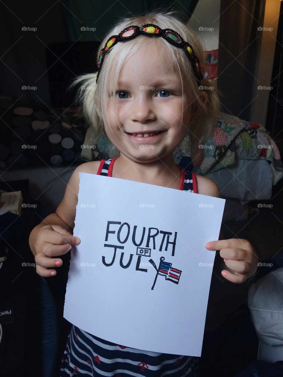 Girl showing fourth of july text on paper