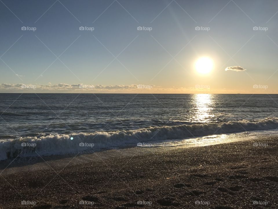 Dusk on Folkestone beach, sun slowly set and sea gently rolling onto the pebbled beach 