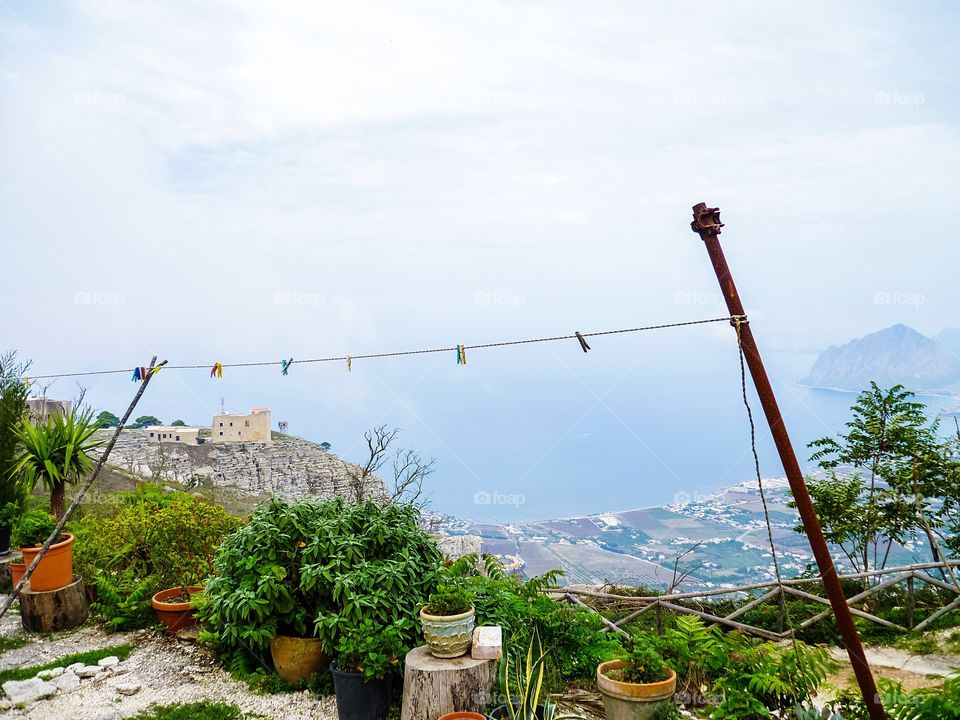 Early morning view of potted plants and an empty clothes line in the hilly town of Erice overlooking Trapani in Sicily, Italy