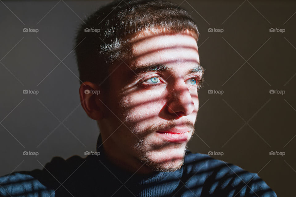 Close-up portrait of young boy looking away against wall with sunlight falling on his face.