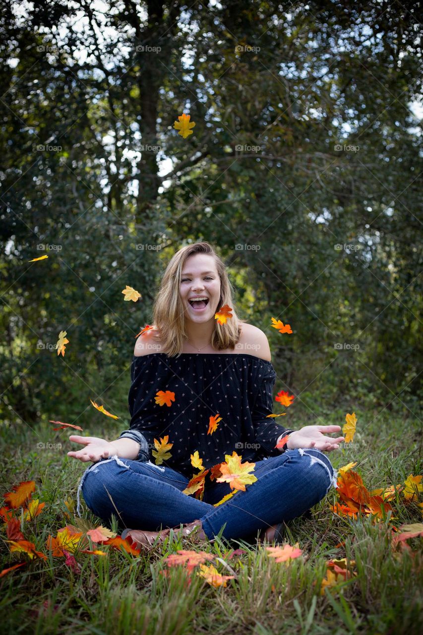 Fall Female Happy Portrait with autumn leaves falling and sitting with nature