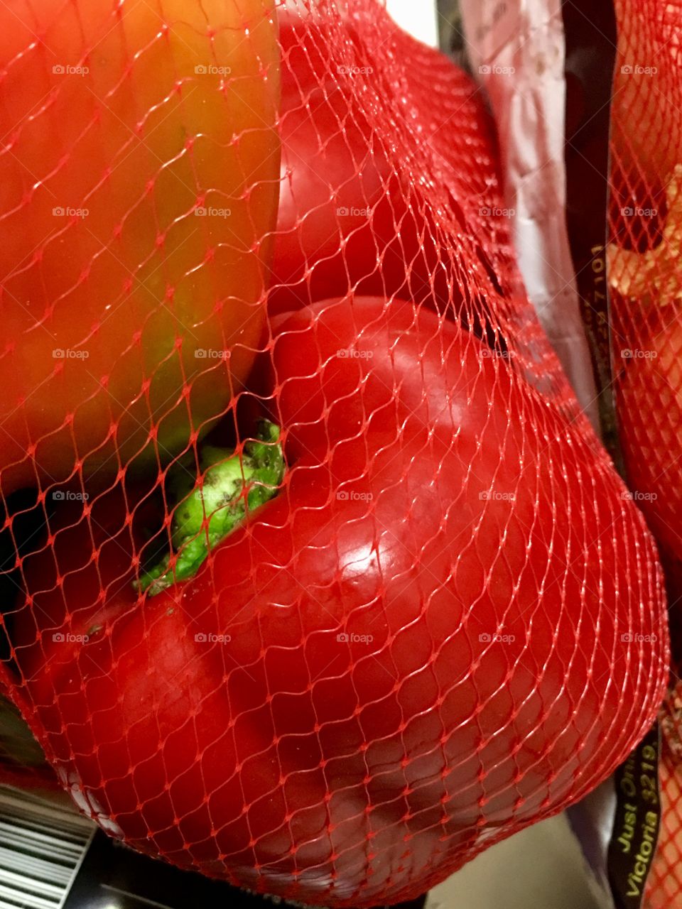 Red sweet bell pepper capsicum in red plastic mesh