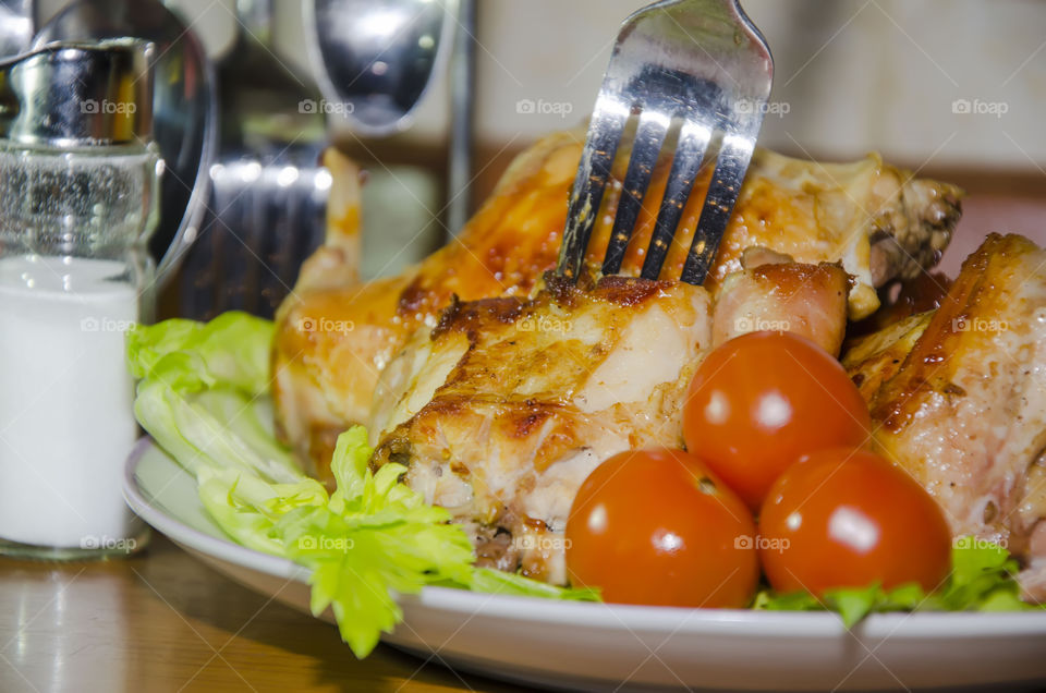 A large portion of roast rabbit with tomatoes and herbs.