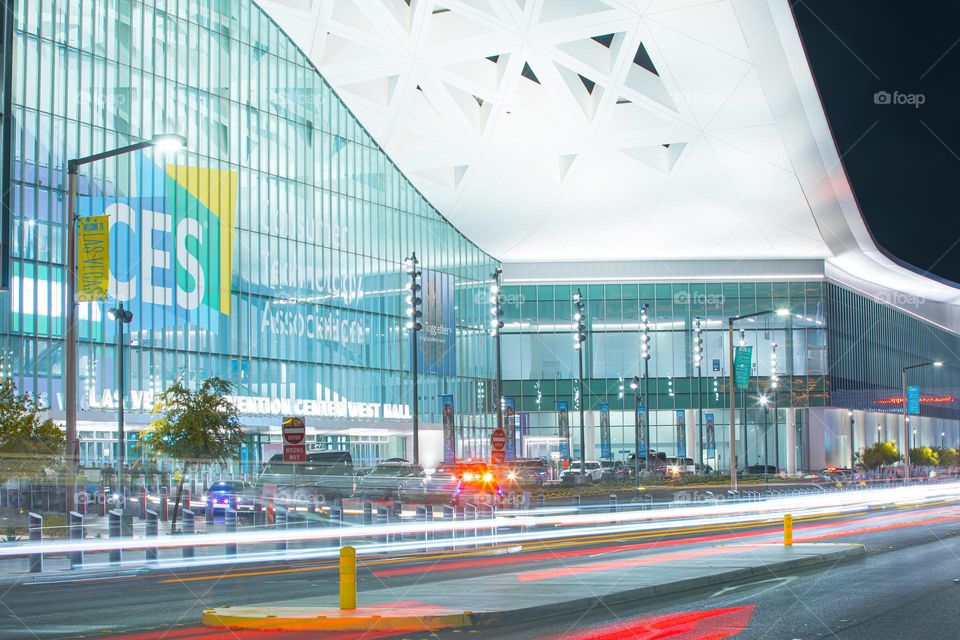 Las Vegas, NV, USA 1-6-2023: Exterior of Convention Center West Hall during CES2023. Logo of CES on glass wall. Light trails from car headlights of traffic passing by. Captured in long exposure.
