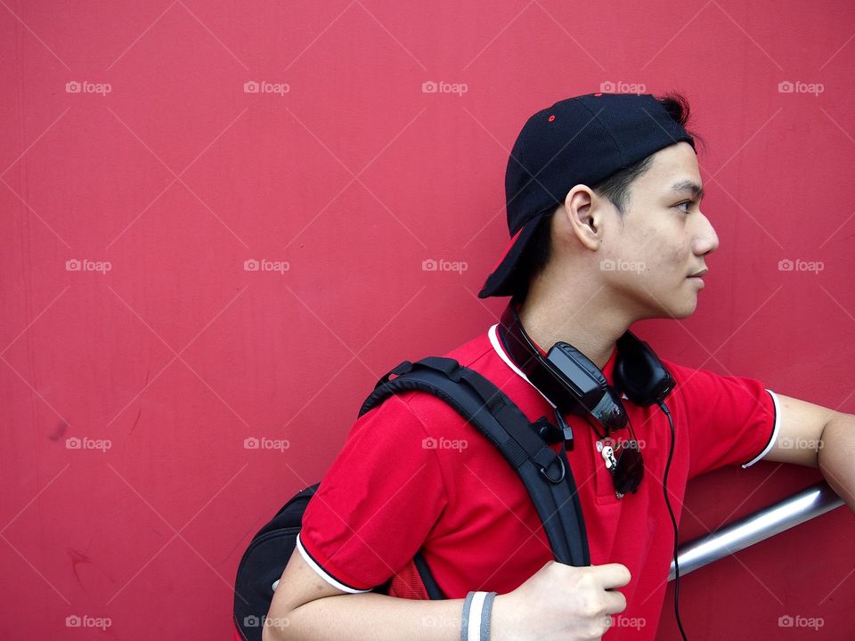 young teenage boy with cap, backpack, sunglasses and earphones
