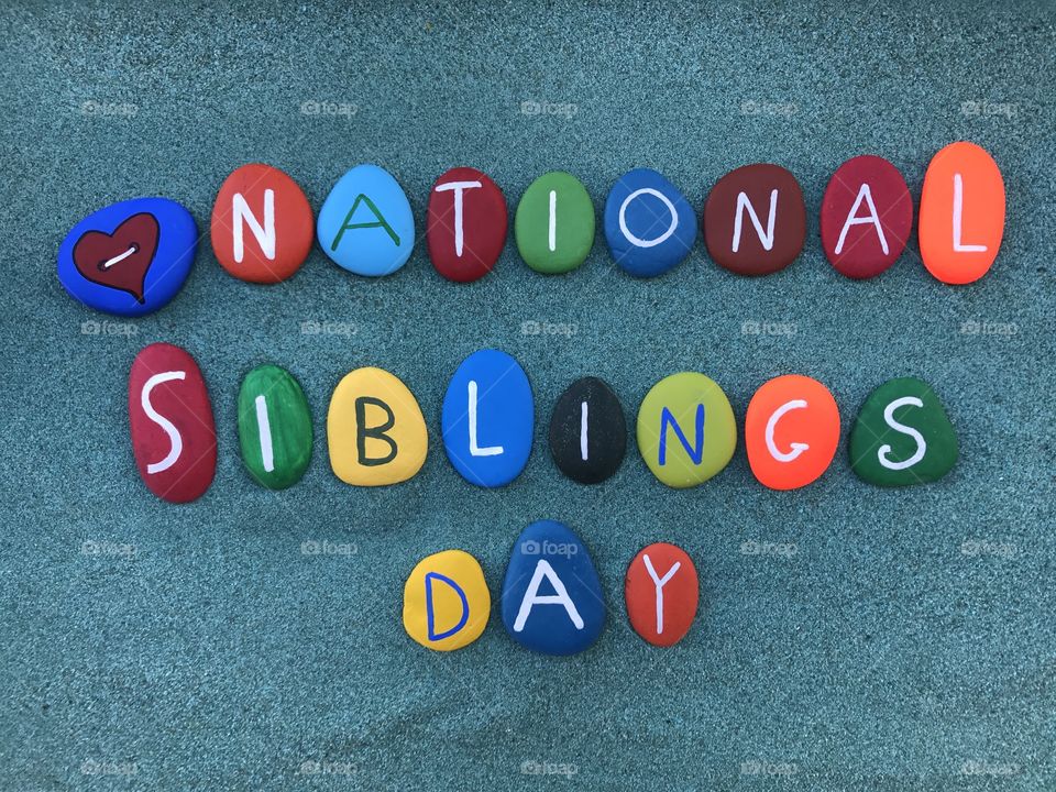 National Siblings Day, celebration with colored stones over green sand