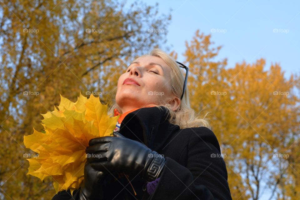 woman beautiful portrait with yellow leaves relaxing outdoor, autumn time