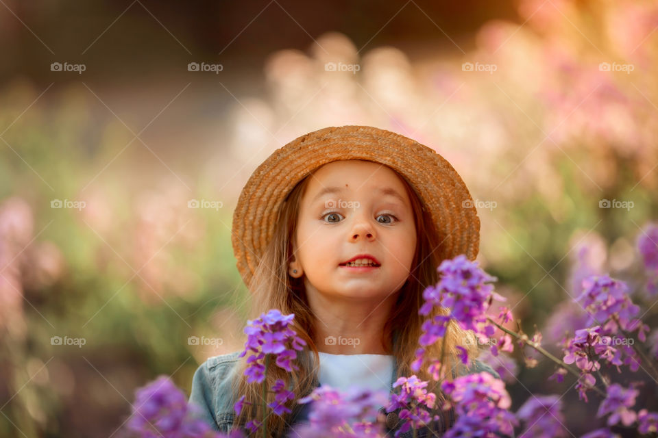 Cute little girl portrait in blossom meadow at sunset 