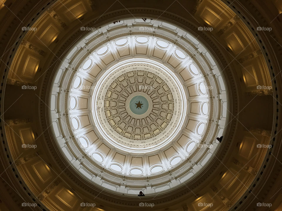 Eye of the Capitol.

In the capitol building of the state of Texas, one can stand at the center of the main atrium, look up, and see a lone star decorating the ceiling. It is a beautiful and awe-inspiring view, especially while listening to the sounds of a choir singing in the atrium itself (which is, sadly, not captured via photography).