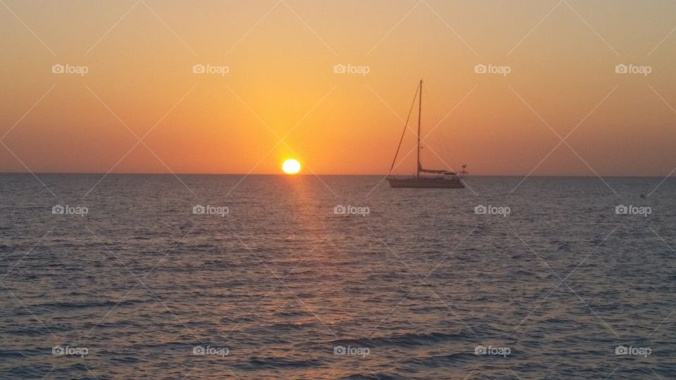 sailboat anchored behind sunset