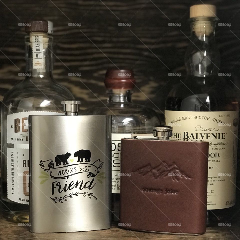 The gifted flasks from two best friends, placed on a shelf next to the liquor that will one day fill them. 
