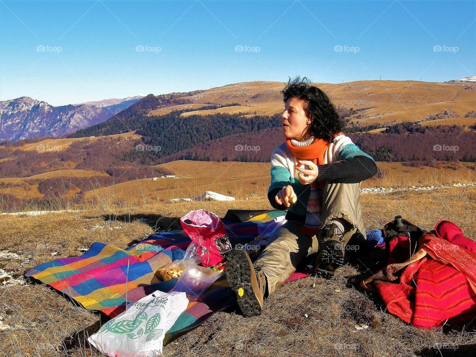 Brunette woman having a snack on top of the mountains, Italy