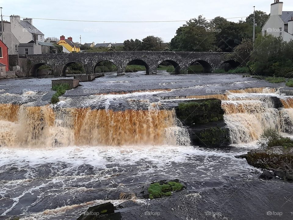 Waterfall with arched stone bridge. Historic town photo in Ireland.