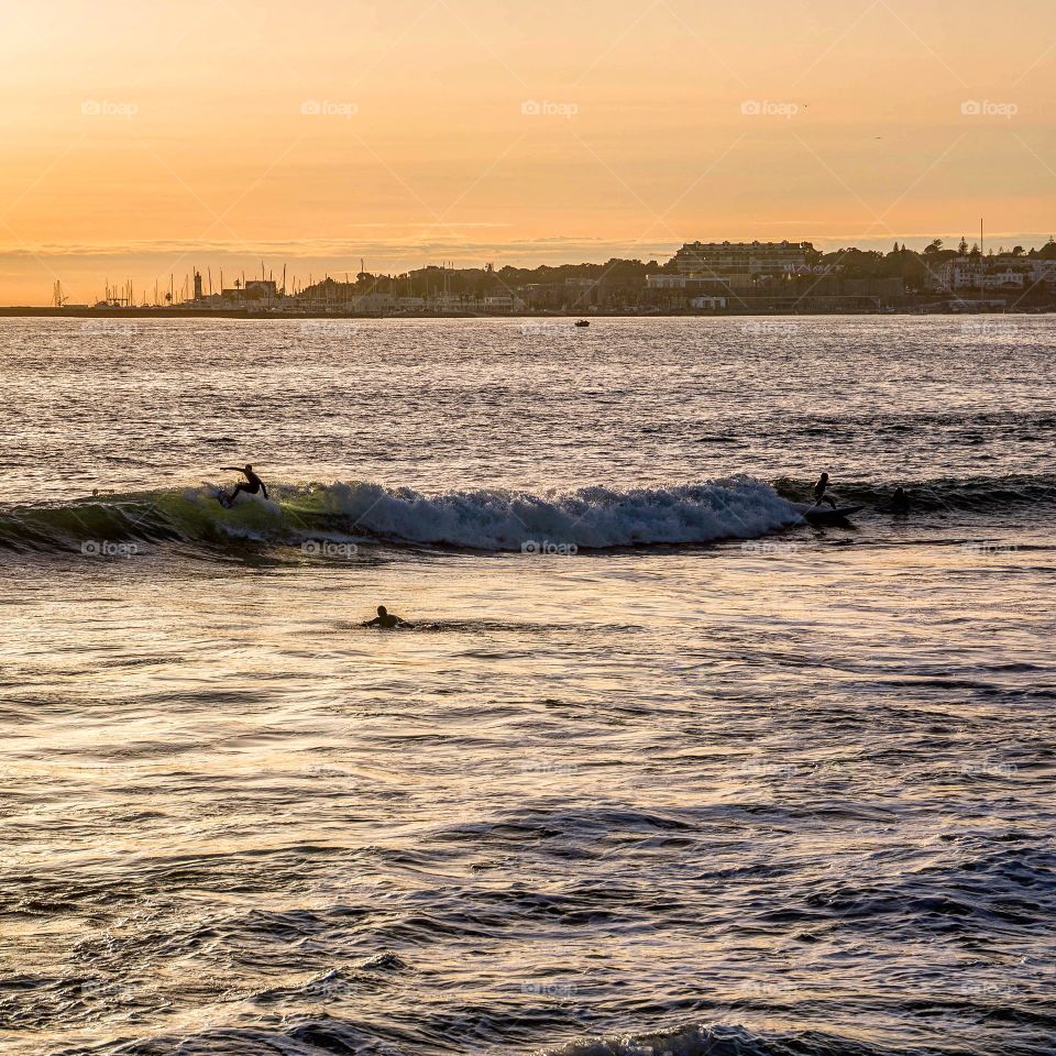2 surfers sharing a wave during sunset