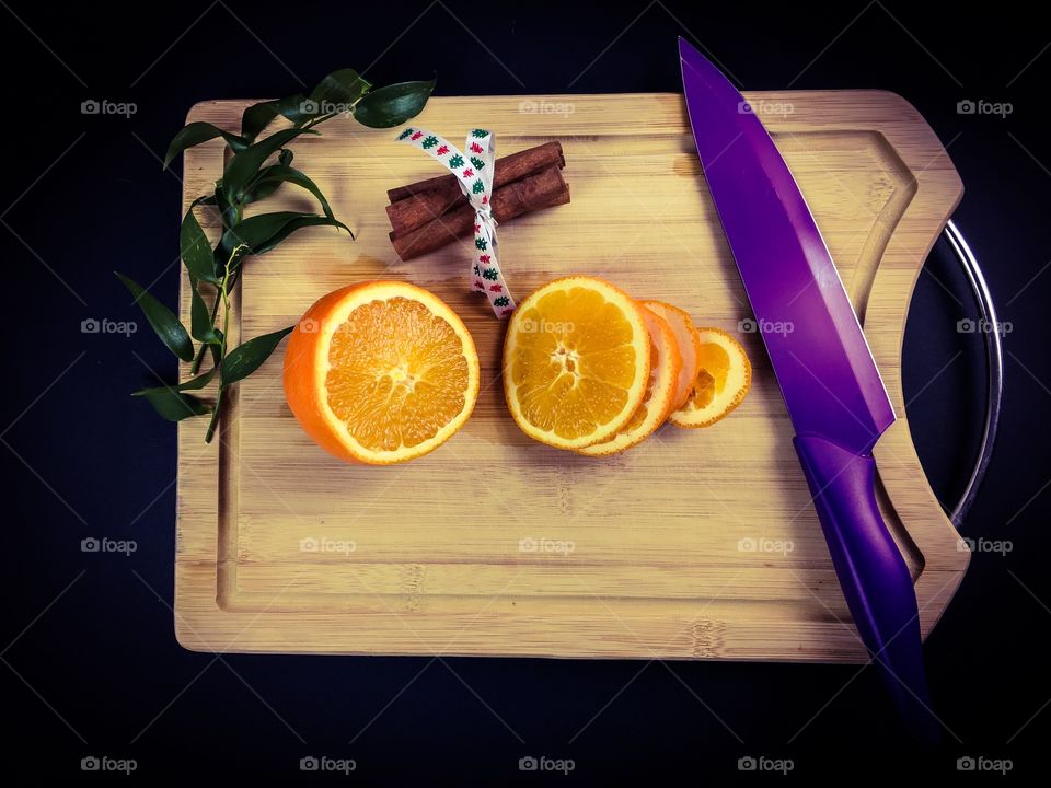 Halved orange on cutting board and kitchen knife