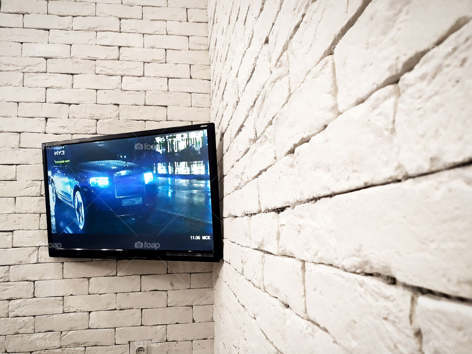 White brick wall with a TV hanging on the corner