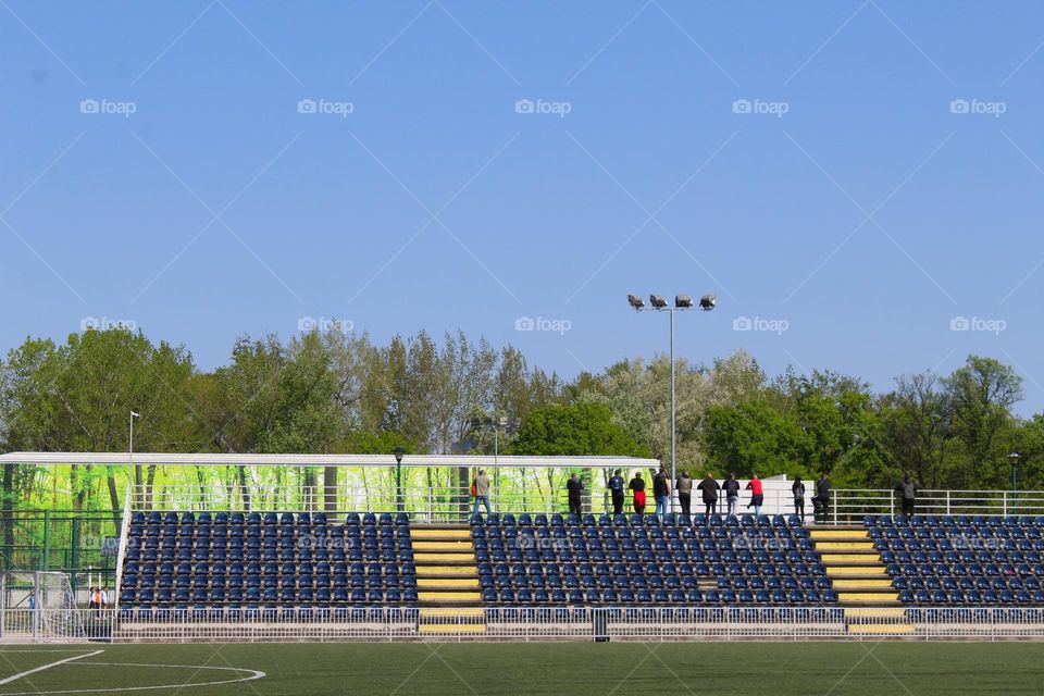 An empty soccer stadium with several people standing and looking at another stadium