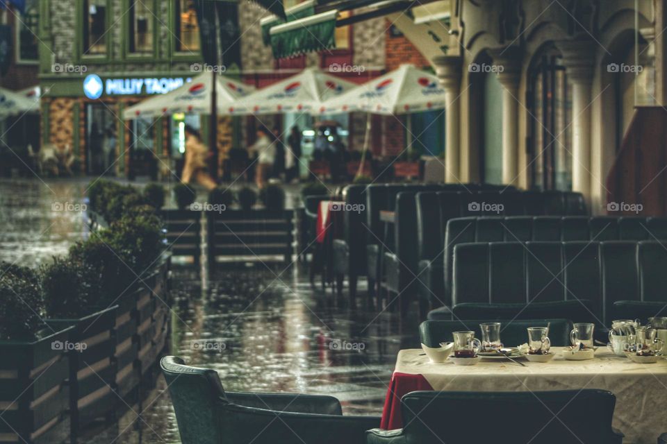 cafe on the street during the rain. leather comfortable armchairs and a white tablecloth. unfortunately the visitors fled due to bad weather