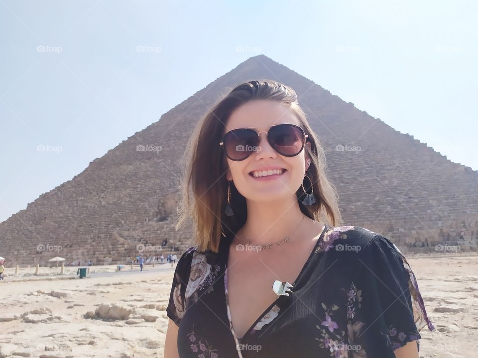 first look to her smile and look to her sunglasses with background great pyramid it's very attractive photo.