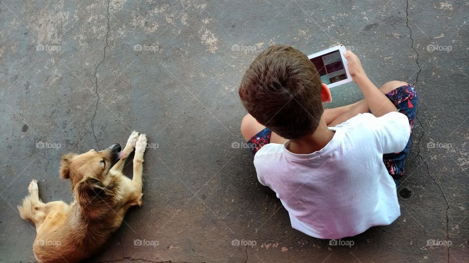 Menino com tablet e um cão.