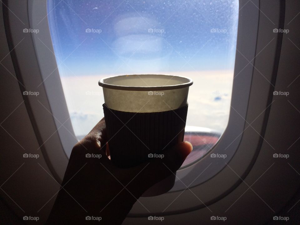 Drinking coffee by window in airplane 