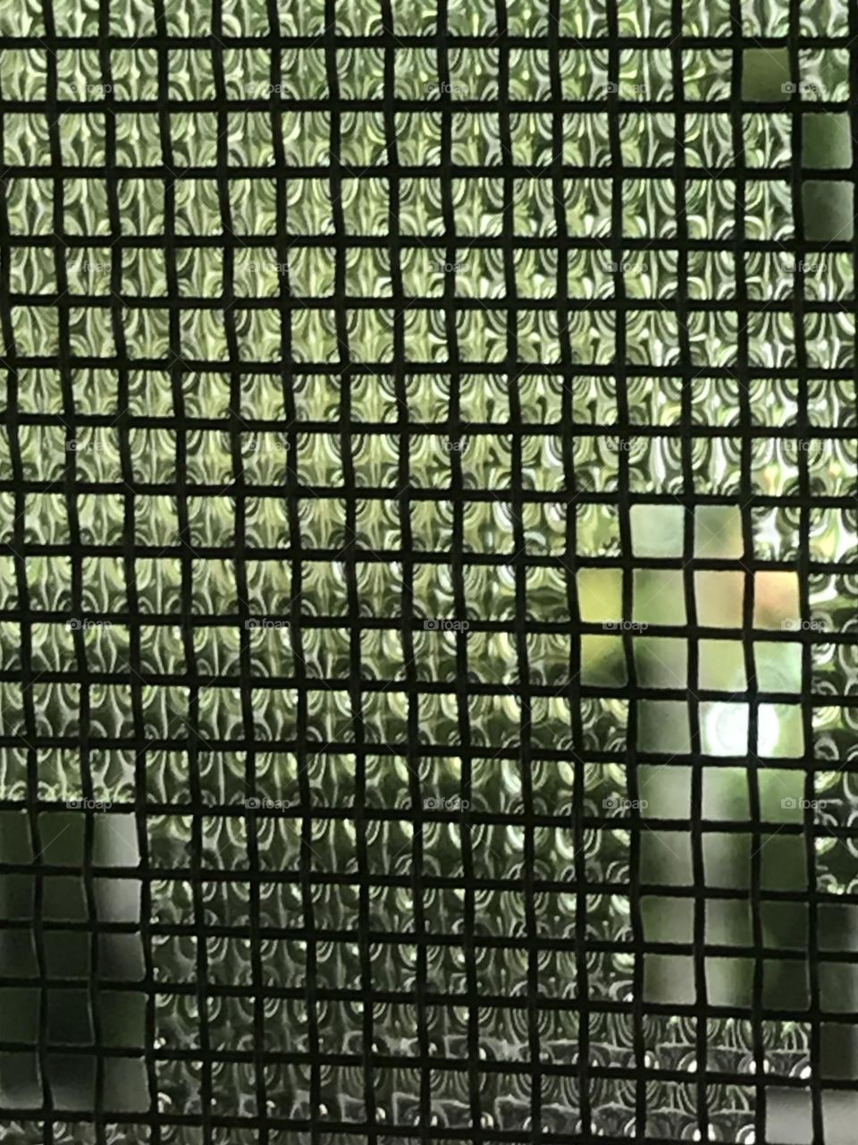 Raindrops entangled in a window net.