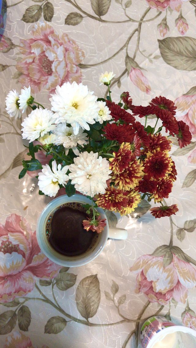 Lovely porcelain cup of coffee with black coffee in it, in the beautiful morning, surrounded by chrysanthemum flowers.