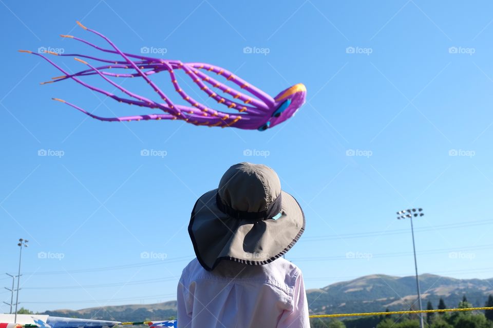 Kid in hat watching a giant colorful kite fly