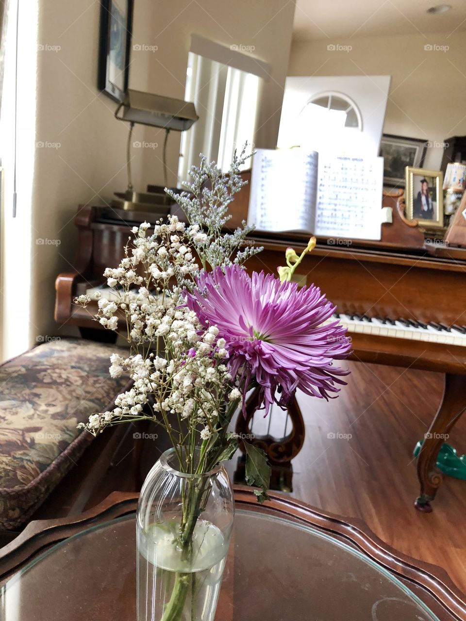 Lilac flowers in vase in front of piano.