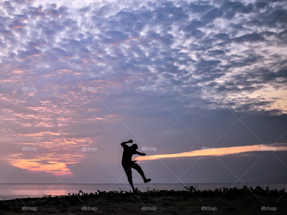 A man doing his morning run on the beach against the morning light