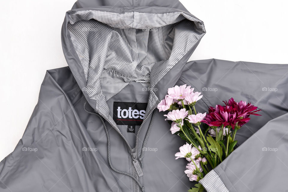 Flat lay of a gray raincoat with a bouquet of flowers