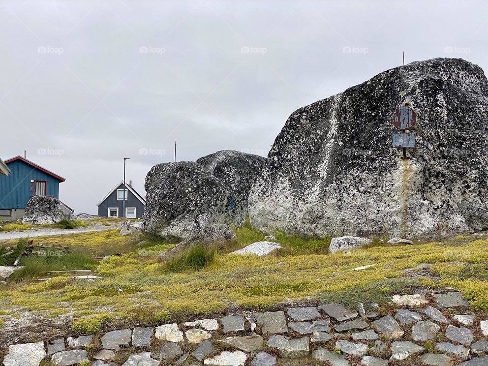 Large boulders and a couple houses in a village in Greenland 