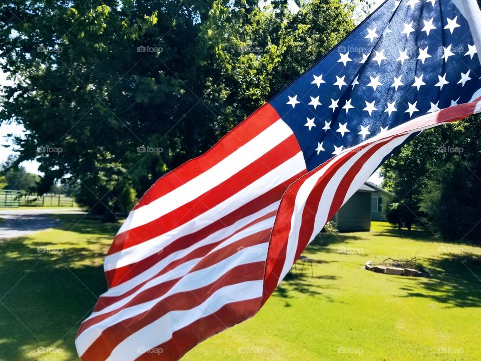 An American Flag waving in the Summer Breeze in the yard of a home