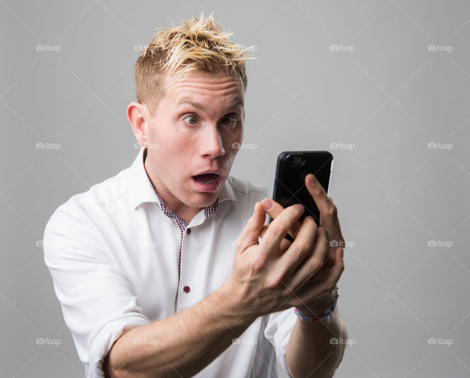 Man with cellular phone acting surprised.