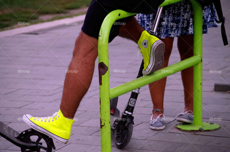 Two people with footbikes resting at railing in Budapest, Hungary.