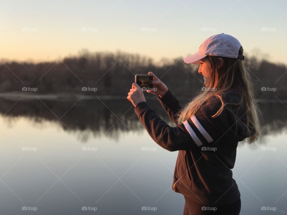 Woman photographing in front of lake