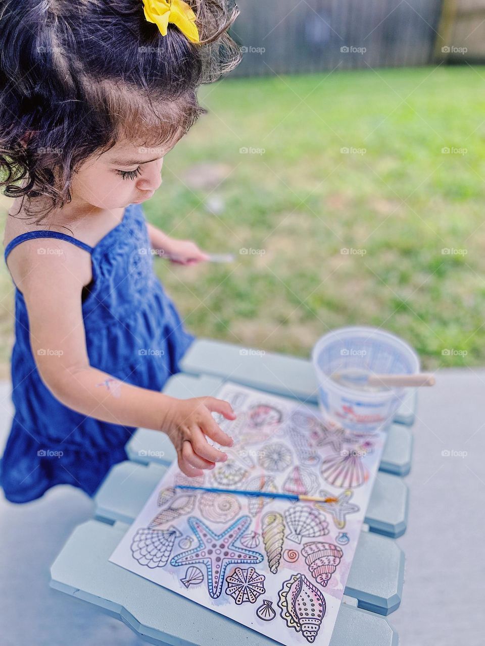 Toddler girl painting seashells outside, toddler using magic paints, fun with painting in the summertime 